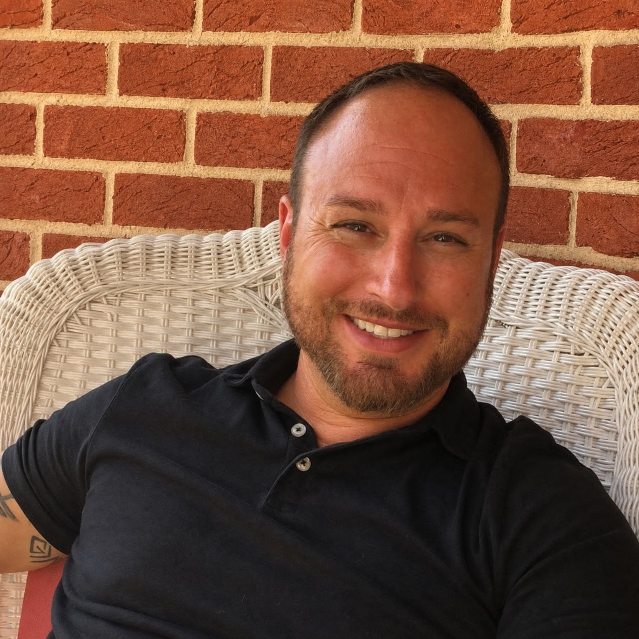 Joseph Trotter of Joseph's Styling Salon seated outdoors and smiling.
